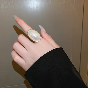 Élégante bague en perle ovale sur le doigt au style français chic, minimaliste et raffiné