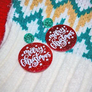 Detailed view of red and green glitter Merry Christmas earrings on a white knit sweater
