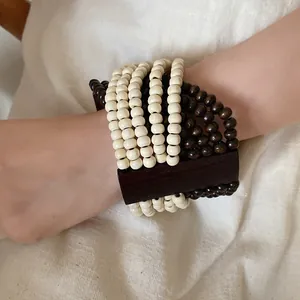 Dettaglio di bracciale bohémien multistrato in perline di legno con inserti scuri