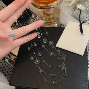 Vista dettagliata di una collana a più strati in perle di vetro trasparente tenuta in mano