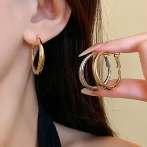 Minimalist smooth gold and silver metal hoop earrings for women shown on an elegant model