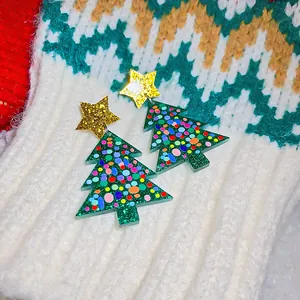 Close-up of festive Christmas tree earrings with glitter gold stars and colorful dots.
