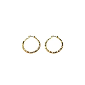 Elegant golden textured hoop earrings with wrinkled wave pattern on white background