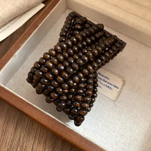 Dettaglio del bracciale multistrato con perline di legno marrone scuro in scatola vintage