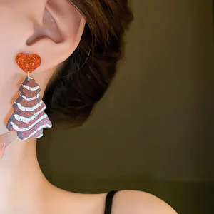 Detailed close-up showing a cute Christmas tree earring with a red glitter heart stud.