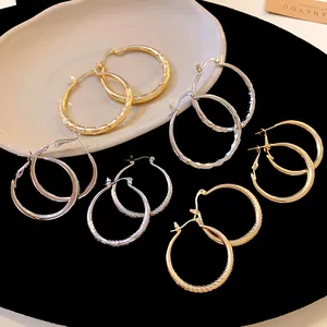 Variety of textured hoop earrings in gold and silver finish on a black background