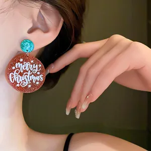 Detailed view of glittery red and green Christmas earrings with Merry Christmas print
