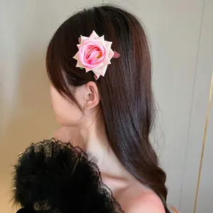 Detailed view of an elegant pink rose flower hair clip worn on a woman's dark hair.
