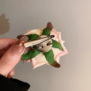Back view detail of pink fabric rose hair clip showing dual metal clip mechanism