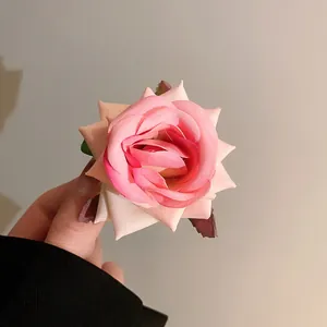 Detailed close-up of a sweet pink rose hair clip showing fabric petal texture.