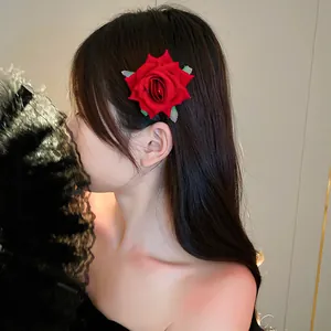 Close-up detail of a vibrant red rose flower hair clip elegantly worn by a model