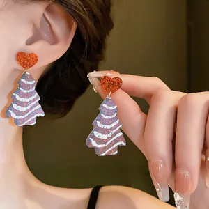 Close-up detail of festive Christmas tree earrings with glittery red heart studs for women