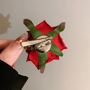 Detailed view of the back of a red fabric rose hair clip showing metal duckbill clip and pin
