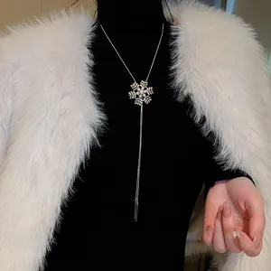 Elegant snowflake pendant long necklace layered on black turtleneck and white fur vest
