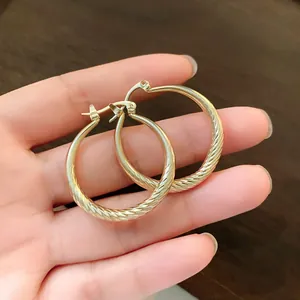 Close-up detail of elegant gold hoop earrings featuring a unique pleated wavy texture