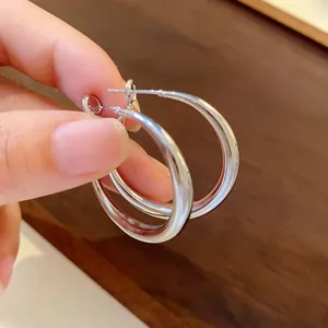 Close-up detail of high-shine minimalist silver-colored thick metal hoop earrings for women
