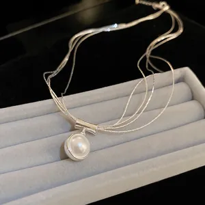 Macro view of an elegant multi-strand silver necklace with a round pearl pendant