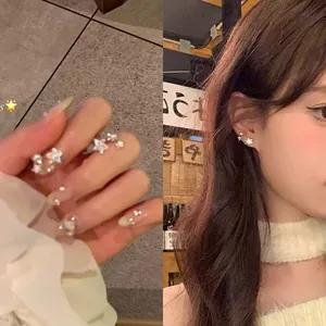 Detailed view of dainty star-shaped cubic zirconia stud earrings worn by a model