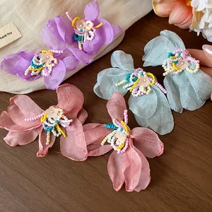 Macro view of handmade beaded chiffon flower earrings in pastel purple, blue and pink.