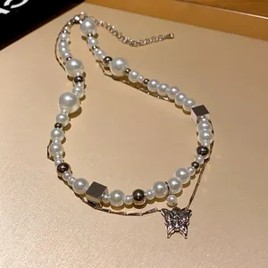Detailed view of vintage French pearl necklace with butterfly pendant and silver cubes