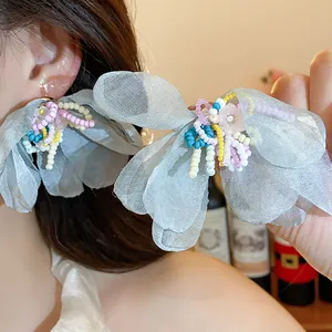 Close-up of chiffon flower earrings featuring colorful glass beads and silver needle studs