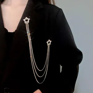 Dettaglio di una spilla a stella in argento con catene e strass su un blazer nero