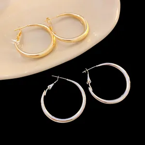 Close-up detail of simple gold and silver metal hoop earrings with wave pattern textures