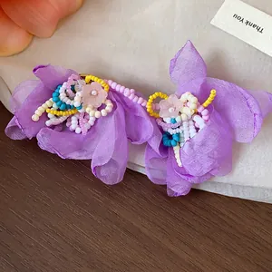 Close-up detail of elegant purple chiffon flower earrings with intricate glass beadwork