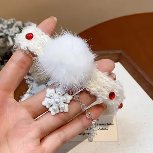 Detail view of a white fuzzy pom-pom and pearl snowflake pendant on a festive choker