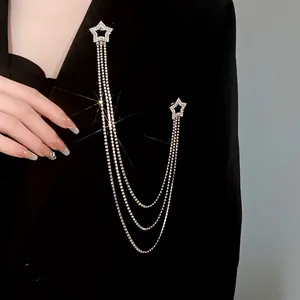 Elegante spilla a stella con nappe e catene di strass scintillanti su blazer nero.