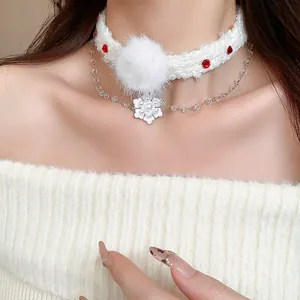 Detail view of a white knitted Christmas choker with snowflake and pearl charm