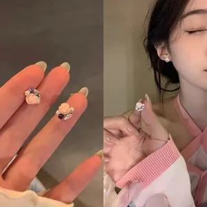 Detailed macro view of pink rose stud earrings with pearls and zircon on model's ear