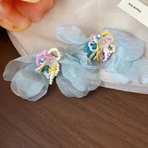 Close-up of elegant blue chiffon flower earrings decorated with multi-colored glass beads