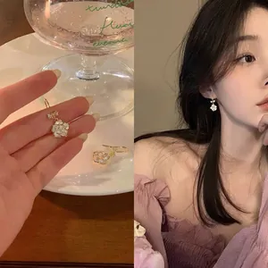 Detailed view of elegant camellia flower earrings with bow on Asian model