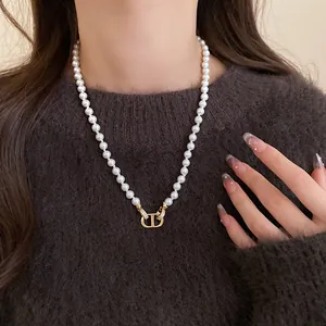 Close-up detail of a French retro faux pearl necklace featuring a gold CD logo pendant