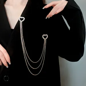 Dettaglio elegante di una spilla a nappine con strass a forma di cuore argento su un blazer nero