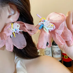 Macro detail of pink chiffon flower earrings with multi-colored glass bead accents