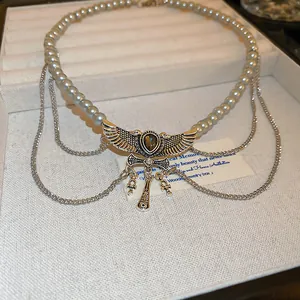 Detailed shot of a vintage winged pendant necklace with grey pearls and Ankh charms