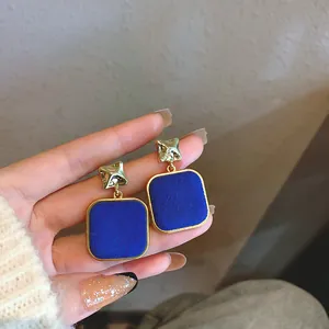 Vista dettagliata di orecchini a perno quadrati in velluto blu Klein vintage con dettagli oro