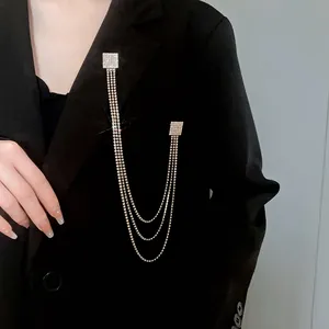 Elegante spilla con nappine in strass quadrati appuntata su un blazer nero di moda.