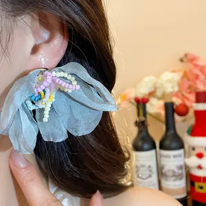 Light blue chiffon flower earrings with colorful glass beads shown on an Asian model