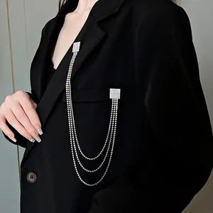 Elegante spilla a nappa con catena in strass quadrati appuntata sul dettaglio del blazer