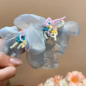 Detailed close-up view of light blue chiffon flower earrings with colorful beads