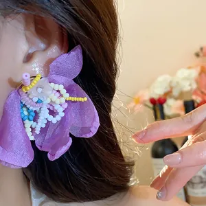Elegant purple chiffon flower earrings with intricate glass bead details in close-up view