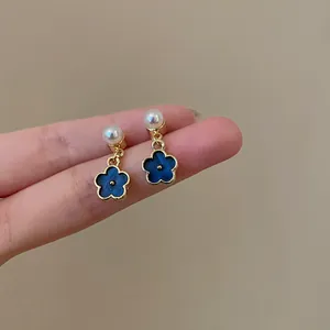 Dettaglio di orecchini retrò francesi con fiori blu Klein ed eleganti perle lucide