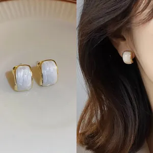 Elegant minimalist gold-tone stud earrings with white resin inlay and model wear view