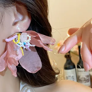 Detailed close-up of large pink chiffon flower earrings with colorful beaded centers