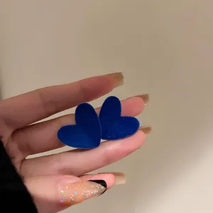 Primo piano di orecchini a cuore blu Klein retrò con texture vellutata su perni in argento