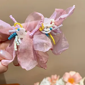 Close-up detail of handmade pink chiffon flower earrings with colorful glass beads.