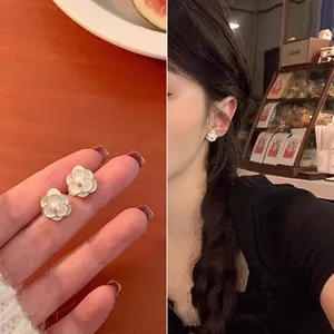 Elegant detail view of mini white flower stud earrings with pearl center worn by model